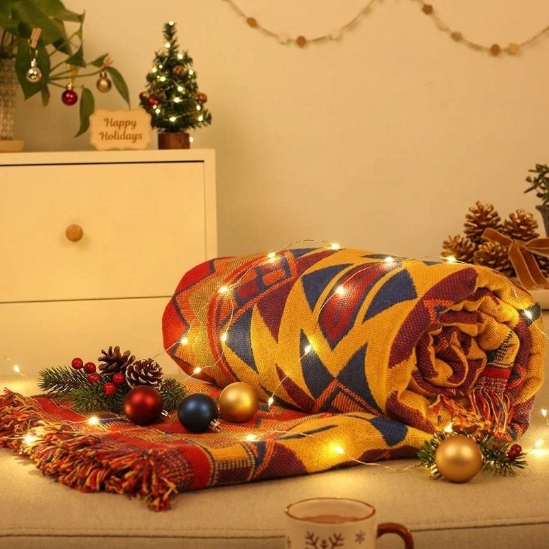 Plaid bohème coloré roulé avec guirlande lumineuse et boules de Noël
